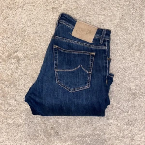 Jacob Cohen blå jeans med knappar - Riktigt snygga Cohëns i storlek 34 men jag har kortat ned dem till 33. Passar mig längd 183. Nyskick, inga tecken pả användning. I slimfit modellen 688C. Nypris pà careofcarl 5399 kr.