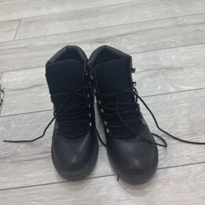 Svarta kängor med snörning - Stilrena svarta kängor med snörning och robust sula. Ovandelen är i skinn och mocka, vilket ger en snygg kontrast. Metallöglor för snörningen ger en cool detalj. Perfekta för höst och vinter.