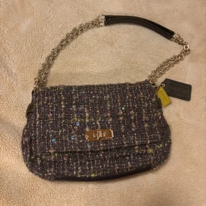 Coach axelväska i tweed och skinn - Axelväska från coach i tweed. Detaljer i brunt skinn och guldfärgad kedjerem. Insidan är fodrad i satin med gula skinnkanter, perfekt skick och storlek