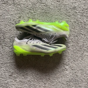 Adidas Crazyfast fotbollsskor grå/gul - Säljer ett par Adidas Crazyfast fotbollsskor i grått med svarta ränder och neongul sula. Skorna har snörning och är tillverkade i syntetmaterial för lätt känsla och bra grepp på planen. Perfekta för dig som vill sticka ut med stil och fart på matchen.