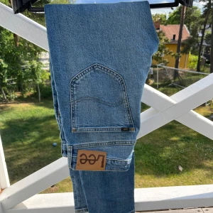 Lee Austin ljusblå jeans W29 L32 - Säljer ett par klassiska ljusblå Lee Austin jeans med raka ben och snygga kontrastsömmar. Jeansen har Lee-logga på bakfickan och läderpatch i midjan. Tillverkade i slitstarkt bomullsdenim och har dragkedjegylf. Perfekta för en avslappnad och tidlös look. Modellen sitter som regualar fit och kostar ca 1200kr helt nya. Jeansen har inga tecken på användning och är som helt nya. Hör av er!