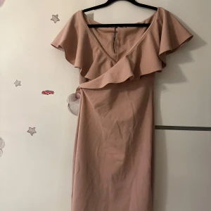  volangklänning från NLY One - Supersnygg  klänning från NLY One med v-ringning och volangdetalj över axlarna. Klänningen är axelbandslös och har en figurnära passform som ger en elegant siluett. Perfekt för dig som vill sticka ut med en stilren look.Du kan hitta mer på min sida.