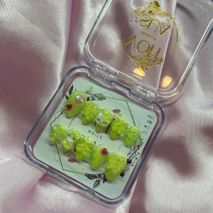 NeonPuff(S);Short Almond - Ett set med gelé press-on naglar i limegrönt med coola 3D-rosetter, hjärtan och söta kattmotiv. Naglarna har en glansig finish och mix av dekorationer i rosa, silver och gult. Formen är short almond och de kommer i storlek S: 15 mm, 11,5 mm, 12 mm, 11 mm, 9 mm. Perfekt för dig som vill sticka ut med färgglada och unika naglar.