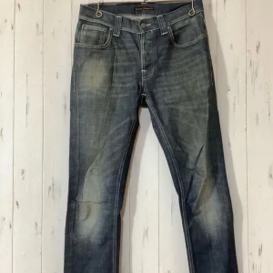 Nudie jeans grim tim old scraped 32/32 - Snygga mörkblå jeans från Nudie Jeans i klassisk femficksmodell. Jeansen har kontrastsömmar, raka ben och en stilren look. Tillverkade i slitstarkt bomullsjeansmaterial. Perfekta för dig som gillar en tidlös och clean stil. Modellen heter "grim tim" och har färgen "old scraped". Väldigt bra skick på jeansen