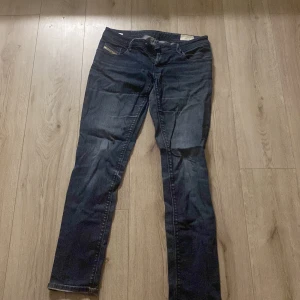 Mörkblå Diesel Nevy jeans W32 L34 - Snygga mörkblå jeans från Diesel, modell Nevy. Klassisk femficksdesign med diskret Diesel Industry-detalj på myntfickan. Jeansen är i stretchigt denim och har en rak passform som sitter bekvämt. Perfekta för dig som gillar stilrena och tidlösa jeans.