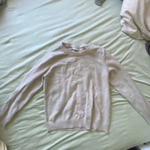 Beige stickad tröja  - En stilren beige stickad tröja från Vila som konstigt nog är i storlek L, men passar som en XXS. Tröjan har rund halsringning, ribbade muddar och är långärmad. Perfekt för lager-på-lager och enkel att matcha med jeans eller kjol.