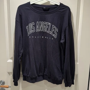 Mörkblå sweatshirt  - Mörkblå sweatshirt med rund halsringning, långa ärmar och ribbade muddar vid ärmslut och nederkant. Perfekt för en avslappnad och cool streetstyle-look.