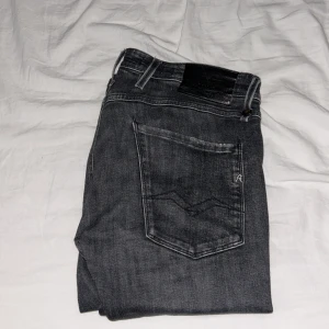 Replay Anbass Slim fit Jeans 33/32 - Säljer ett par Replay Anbass Slim fit jeans, mörk grå! Feta slitningar, dock defekt i skrevet som blivit lagad (Se bild 4!) 