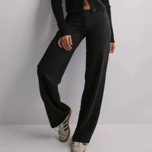 Svarta kostymbyxor rak modell  - Snygga svarta kostymbyxor med låg midja och raka ben. Byxorna har klassisk knapp och dragkedja framtill samt bälteshällor. Perfekta för en clean och stilren look. 