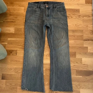 Blå bootcut jeans från Balenciaga - Säljer ett par blå bootcut jeans från Balenciaga med råa, fransiga benslut. Jeansen har klassisk femficksdesign, normal passform och är tillverkade i bomull. Snygg tvätt med slitningar och Balenciaga-logga bak i midjan. Sitter som en 32 i midjan o justerad att passa min längd bättre 178cm