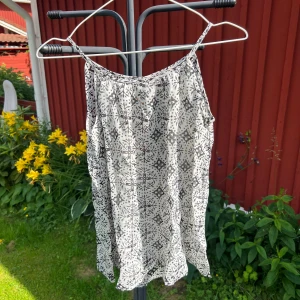 Vit och svart paljettopp från Indiska - Supersöt vit och svart topp från Indiska med tunna axelband, och små paljetter här å där.  Storlek S