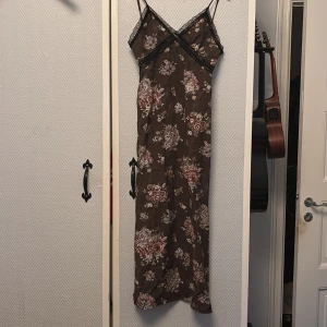 Blommig klänning med slit - Jätte fin brun klänning med blommor från hm. Midi/maxi klänning