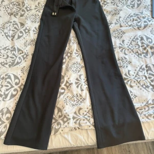 Svarta vida byxor med låg midja - Snygga kostymbyxor med låg midja och vida ben. Perfekta för dig som gillar en trendig och avslappnad look. Byxorna har klassisk design och passar till många olika stilar. 