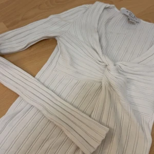 Vit ribbad tröja  - Säljer en vit långärmad ribbad tröja med snygg knut framtill. Tröjan har smickrande passform och är perfekt för dig som gillar stilrena och trendiga plagg. Superenkel att matcha med jeans eller kjol.