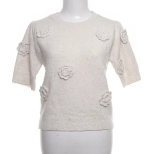 Vit stickad tröja med blommor JS Millenium - Superfin vit stickad tröja från JS Millenium med korta ärmar och 3D-blommor som dekoration på både fram- och baksida. Tröjan har rund hals och ribbad kant nedtill. Perfekt för dig som gillar unika detaljer och vill ha en mysig men stylish look. Pris kan diskuteras!❤️