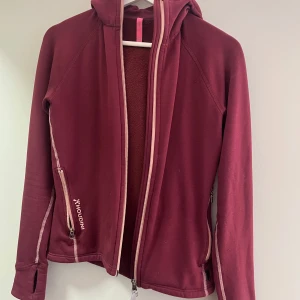 Vinröd fleecejacka från Houdini - Säljer en vinröd fleecejacka från Houdini med huva. Jackan har långa ärmar med tumhål och två sidofickor med dragkedja. Inga noppor. Storlek xs