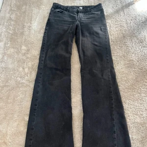 Svarta bootcut jeans  - Snygga svarta jeans från DIVIDED i bootcut-modell med klassisk femficksdesign. Jeansen har en mörk tvätt och raka ben som blir vidare nedtill. Materialet är jeans och midjan är normal. Perfekt för dig som gillar en retro vibe och vill ha ett par coola jeans. Midjemått - 34 cm innerbenslängd- 78 cm