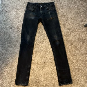 Svarta nudie jeans  - Tjena Säljer ett par svarta jeans från Nudie Jeans i storlek W28 L32. De har klassisk femficksdesign, snygga slitningar och Nudie-logga på bakfickan. Jeansen är tillverkade i stretchig denim för skön passform och har en mörk tvätt med coola detaljer. Kontakta vid frågor. Dem är lite skinny men det går att stretcha ut.