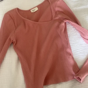 Rosa ribbad långärmad topp från Gina Tricot - Säljer en ljusrosa ribbad topp från Gina Tricot, basically basics-kollektionen. Modellen har lång ärm, oneshoulder-skärning och är figurnära i storlek S. Perfekt att styla med jeans eller kjol för en chill look. Materialet är mjukt och stretchigt, vilket gör den skön att bära hela dagen.