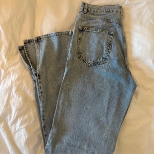 Ljusblå high waist jeans med slits - Säljer ett par ljusblå jeans med hög midja och raka ben. Modellen har klassiska fem fickor och snygga slitsar vid bensluten som ger en cool vibe. Perfekta till sneakers eller boots. Materialet är jeans och passformen är loose.