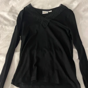 Svart långärmad topp med spets Gina Tricot - Svart långärmad topp från Gina Tricot med snygg v-ringad hals och dekorativ spetskant. Mjuk och skön bomullskvalitet som sitter bra på kroppen. Perfekt för dig som gillar stilrena och enkla plagg med en liten twist. Använd max 3 gånger. Intimissimi doup (stav) från gina tricot. Super skön och passar både till vardags och lite festligare tillfällen!❤️❤️