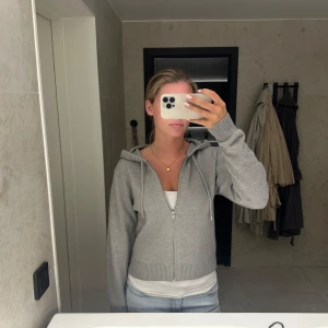 Grå hoodie med dragkedja och huva - Säljer en ljusgrå hoodie med dragkedja och huva från Gina Tricot. Storlek M ingen prislapp men aldrig använd 