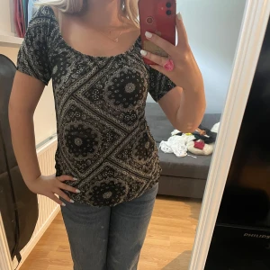 Svart mönstrad offshoulder topp  - Säljer en svart och vit topp från Miss Molly i storlek M. Toppen har ett coolt paisley-inspirerat mönster och kan bäras både med vanlig halsringning eller offshoulder. Materialet är mjukt och stretchigt, perfekt till jeans. Kortärmad och loose fit.