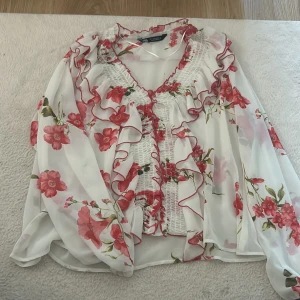 Blommig volang blus från Zara - Super söt somrig blus från Zara. Blusen är V-ringad och har ett blommigt tryck, passar perfekt till fest och varma dagar!!