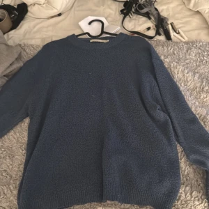Blå stickad tröja f - Mysig blå stickad tröja  med rund hals och ribbade muddar vid ärmslut och nederkant. Perfekt för dig som gillar en enkel och chill stil. Tröjan har lång ärm och loose passform, vilket gör den skön att bära under kyliga dagar.