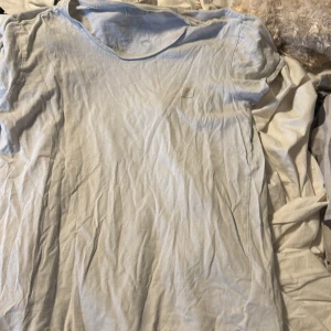 Vit t-shirt från Prominent - Vit t-shirt från Prominent med svart tryck i cirkel på ryggen. Klassisk rund hals och korta ärmar. Mjuk bomullskvalitet som känns chill mot huden. Perfekt för dig som gillar cleana och stilrena plagg med en twist.