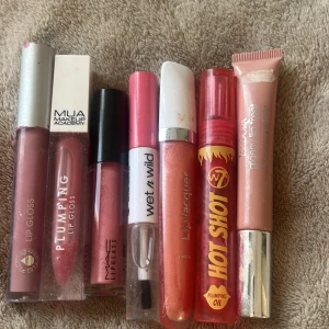 Mix av läppglans och lip oils - Säljer ett gäng läppglans och lip oils från MUA, MAC, Wet n Wild, W7 Hot Shot, Lindex och Isadora. Färgerna varierar från nude och rosa till persika och korall, med både glossiga och plumping-effekter. Perfekt för dig som gillar glansiga läppar och vill testa olika märken.