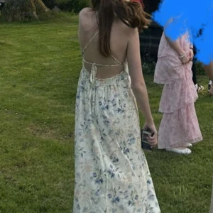 Blommig långklänning med öppen rygg - Säljer en superfin långklänning med blommigt mönster i ljusa toner av blått, gult och vitt. Klänningen har smala axelband, v-ringning och en snygg öppen rygg med snörning. Perfekt för sommarens alla tillfällen, riktigt flowy och skön i materialet. Den är endast använd en gång, då använde jag den som en balklänning.”” Detta är de bästa bilderna jag hittade på klänningen men kontakta mig om du vill ha fler! Storleken är m/l men passar mig som har xs/s. I ryggen kan man spänna in väldigt mycket.