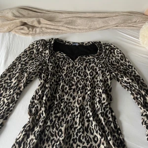 Leopardmönstrad blus från ONLY - Säljer en leopardmönstrad blus från ONLY med leopardmönster i beige, svart och bruna toner. Blusen har v-ringad hals och är tillverkad i ett lätt, flowy material som ger en cool vibe. Perfekt för dig som gillar att sticka ut med djurmönster!