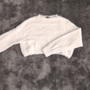 Fin stickad tröja ifrån topshop - En fin stickad tröja ifrån topshop. Runt midjan är det 52 cm. Längden är 36cm. Har också några trådar som hänger ut ifrån ärmen som man kan se lite av på andra och sista bilden. Annars är det inget fel på den.