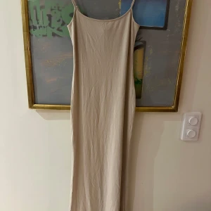 Beige långklänning från Gina Tricot - Säljer en stilren beige långklänning från Gina Tricot. Klänningen har smala axelband och en tight passform. Den går nästan ner till marken för mig som är 174 cm!