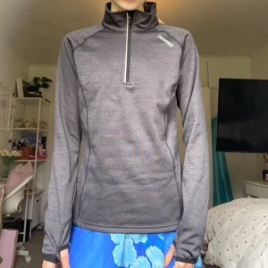 Mörkgrå träningströja - Sportig mörkgrå långärmad träningströja från Karhu med half zip och hög krage. Tröjan har tumhål i ärmsluten och är gjord i ett mjukt, syntetiskt material som andas. Inuti är det fleece! Perfekt för löpning eller utomhusaktiviteter under kyligare dagar😻Använd någon gång, mycket bra skick!