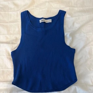 Blå ribbad linnetopp från Zara - Snygg blå ribbad linnetopp från Zara med croppad passform. Toppen är ärmlös och har rund halsringning, perfekt för en chill och trendig look. Materialet är stretchigt och följsamt, vilket gör den superbekväm att bära.