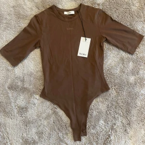 Brun bodysuit från Àvora - Snygg brun bodysuit från Àvora. Helt oanvänd med lapp på