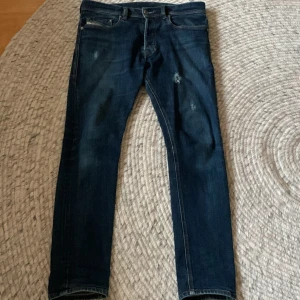 Mörkblå skinny jeans från Diesel - Snygga mörkblå jeans från Diesel med klassisk femficksdesign och diskreta slitningar framtill. Jeansen har smal passform och raka ben, tillverkade i mjukt denimtyg med snygga kontrastsömmar. Perfekta för dig som gillar en stilren och modern look.