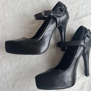 Svarta pumps med rem från Dinsko - Fina knappt använda skor med klack som är ca 10,5cm hög. Har något litet märke på ena, se bild.