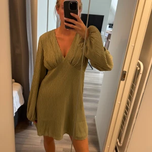 Olivgrön klänning - Säljer denna jättefina cocktailklänning från NAKD, helt oanvänd med prislapp kvar!