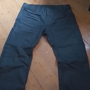 Svarta jeans från KappAhl, stl 164 - Snygga svarta jeans från KappAhl med coolt Black Rock Genuine-märke bak. Klassisk femficksmodell med raka ben och snygga detaljer på bakfickorna. Perfekta för dig som gillar en stilren look med lite edge.
