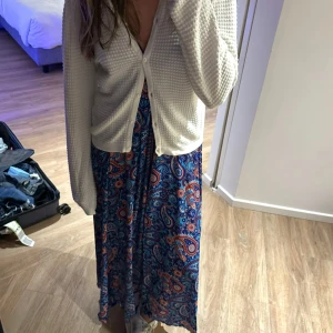 Blå paisleymönstrad långklänning - Säljer en färgstark långklänning med paisleymönster i blått, rött och vitt. Klänningen har v-ringning, smala axelband och fin lång öppen rygg. Materialet känns lätt och luftigt. Köpt i Grekland! Kan gå ner i pris vid snabb affär!