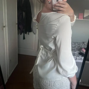 Vit blus med knyt i midjan - Säljer en stilren vit blus med rund halsringning och knytband i midjan. Blusen har trekvartärmar med resår vid ärmslut och är tillverkad i ett lätt, flowy material som ger en luftig känsla. Perfekt att styla med både jeans och kjol.