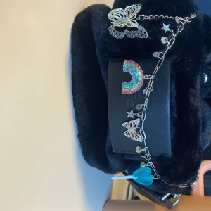 Nyckelring/ bagscharm/ kedja - Cool kedja dekorerad med fjärilar, stjärnor, regnbåge och en blå klubba. Perfekt för dig som gillar unika accessoarer och vill sticka ut. Nypris 250 kr, har använts 2-3 ggr som smycke på väska.  Materialet vet jag ej, men ev stål/metall och regnbåge/klubba i plast. Se tidigare annonser för mer info.