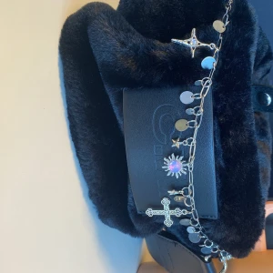 Nyckelring/ bagcharm/ kedja - Kedjan är silverfärgad med coola berlocker som stjärna, kors och sol med lila sten. Perfekt statement piece! Nypris 200. Material kan vara stål/metall tror jag. Se första annonsen för mer info. 