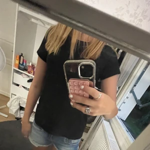 Svart basic t-shirt - Enkel svart t-shirt med rund hals och korta ärmar. Perfekt till jeansshorts eller under en hoodie. Snygg och stilren modell som passar till det mesta. Skön passform och lätt att matcha med andra plagg.