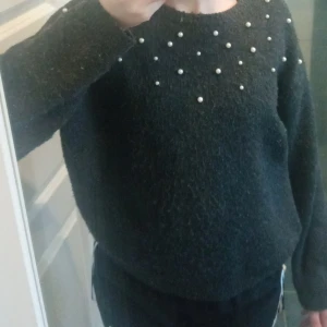 Mörkgrå stickad tröja med vita pärlor - Lite noppig mörkgrå tröja med vita pärlor från H&M. Har använts ett fåtal gånger och har tvättats få gånger. Inte en svart tröja, utan mörkgrå.