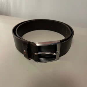 Tommy Hillfiger bälte  - Snyggt brunt bälte från Tommy Hilfiger i skinn med silverfärgat spänne. Bältet har en stilren design och är knappt använt. Det är 105 cm långt. Hör av er om ni har frågor 