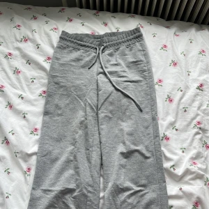 Grå mjukisbyxor från 157, XS - Grå mjukisbyxor från 157 i storlek XS. Byxorna har resår i midjan med snörning och är tillverkade i mjukt bomullsmaterial. Finns en fettfläck på byxan därför säljs den billigt!